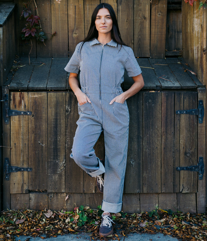 A woman wearing Bodie Women's Coverall in indigo railroad color by Deso Supply Co.