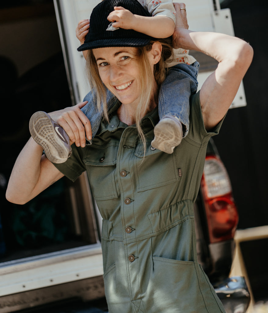 A woman wearing Homewood Coveralls in dark sage color by Deso Supply Co. 2