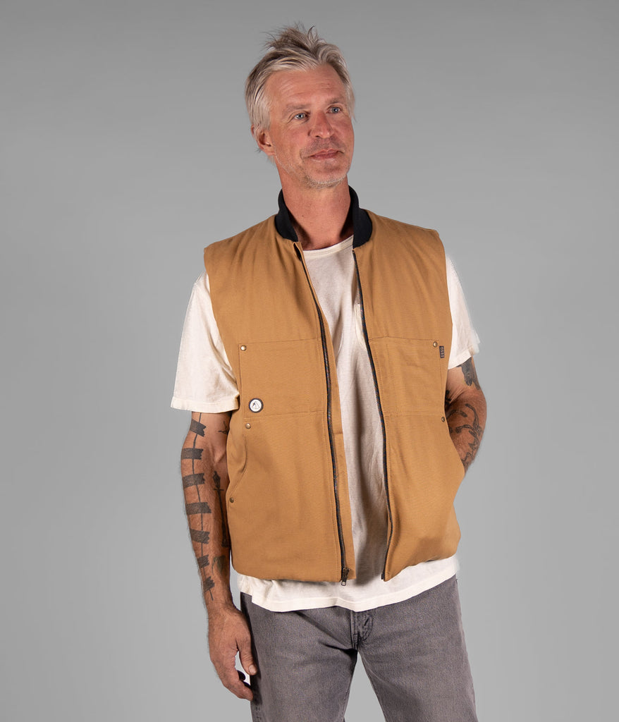 A man wearing a Hard Chore Vest in burley wood color by Deso Supply Co.
