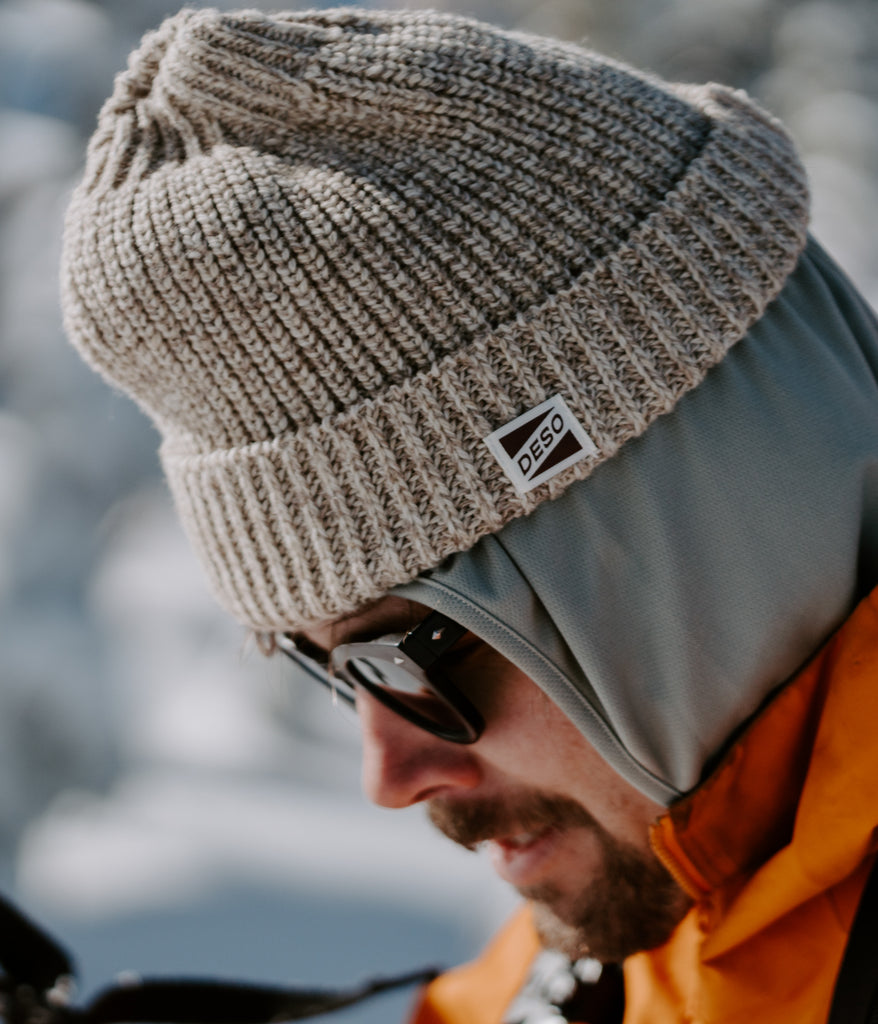 A man wearing sunglasses and a Mariner Cuff Beanie in oatmeal color by Deso Supply Co.
