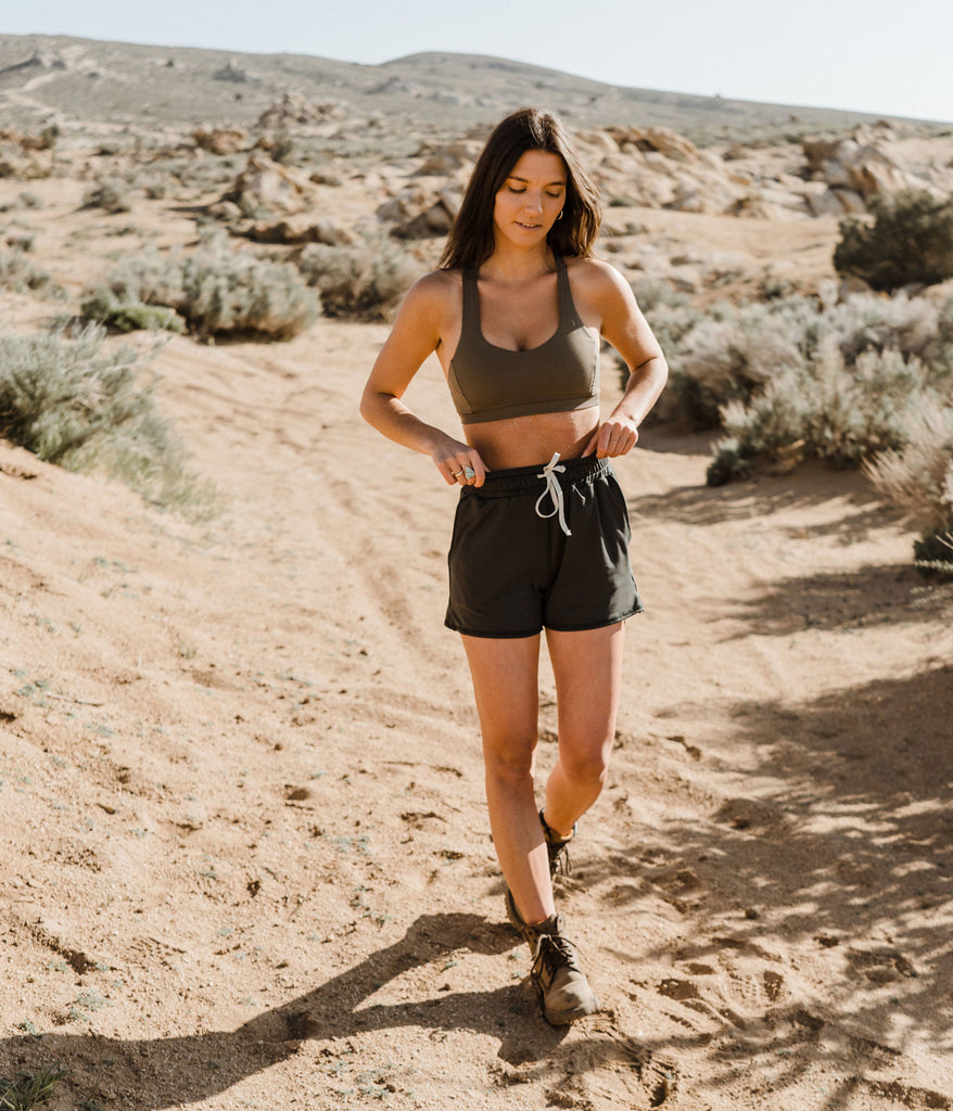 A woman outdoors wearing the Madora Short in forest black color by Deso Supply Co.