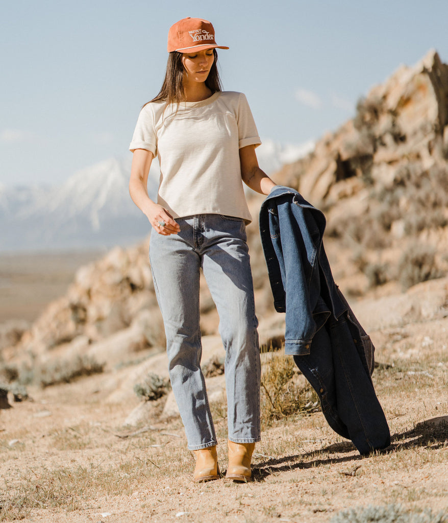 A woman in jeans and a hat wearing Kalmia Oversized Baggy Tee in beige color