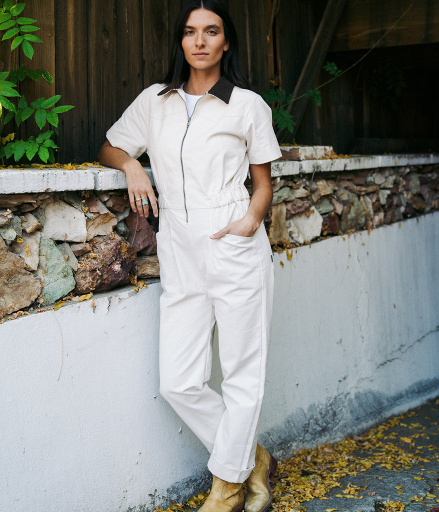 A woman wearing bodie coverall in natural color by Deso Supply Co.