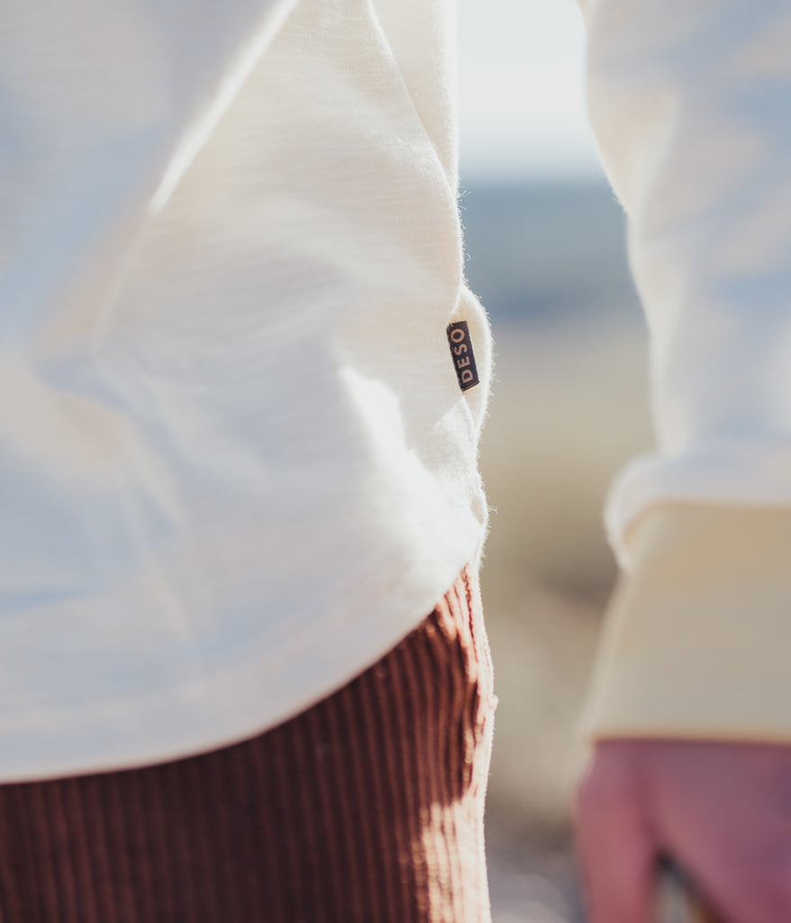 A close-up of a man wearing the Primary Slub long sleeve in beige color by Deso Supply Co. 1