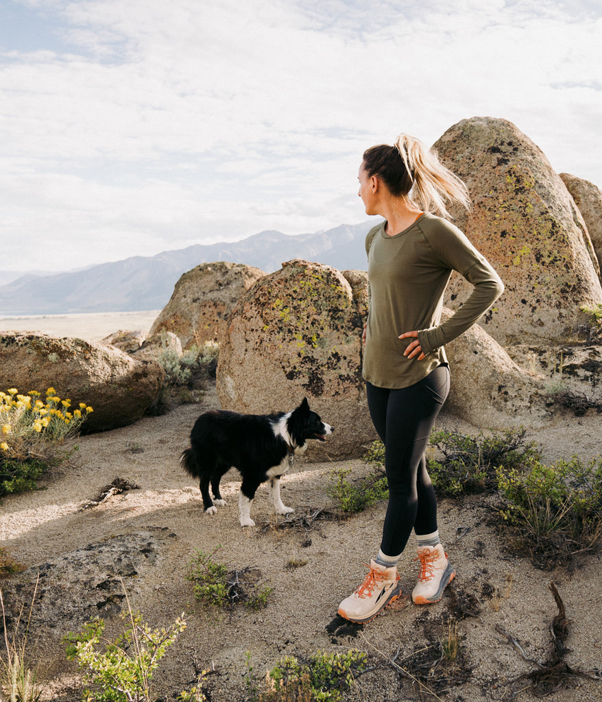 A woman outdoors with a dog wearing Shirley Long Sleeve in olive color by Deso Supply Co.