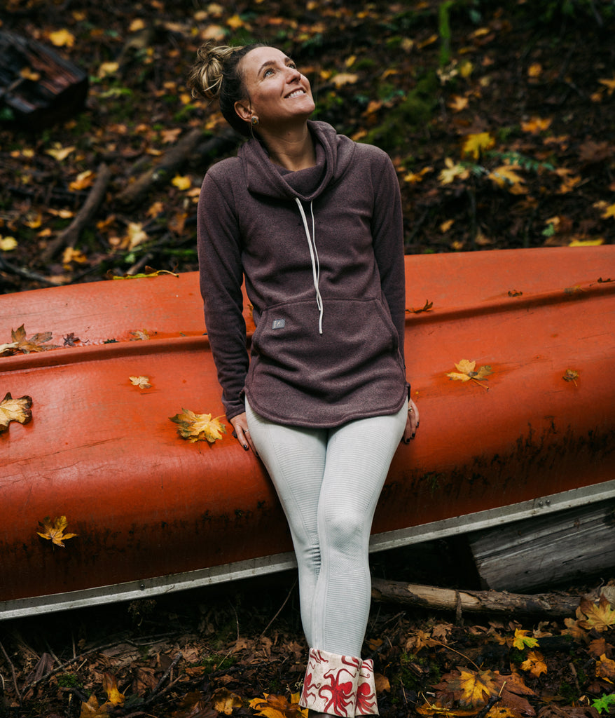 A person leaning on an orange boat wearing Tallac Pullover in mauve color