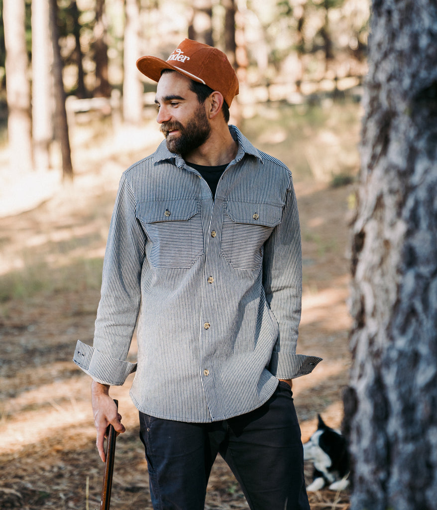 A man wearing an Indigo Dyed Workshop Shirt in railroad color by Deso Supply Co.