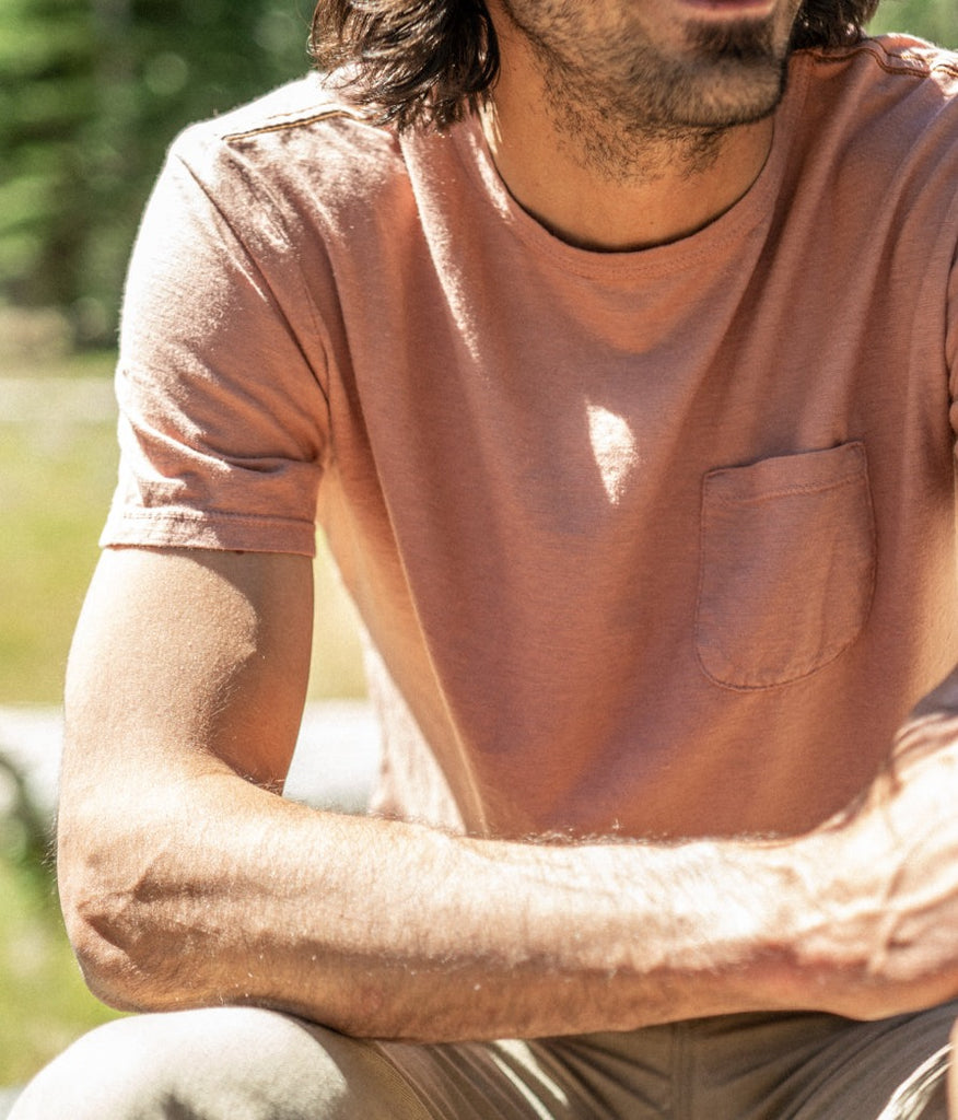 A close-up of a man wearing a Men's Primary Pocket Tee in clay color by Deso Supply Co.