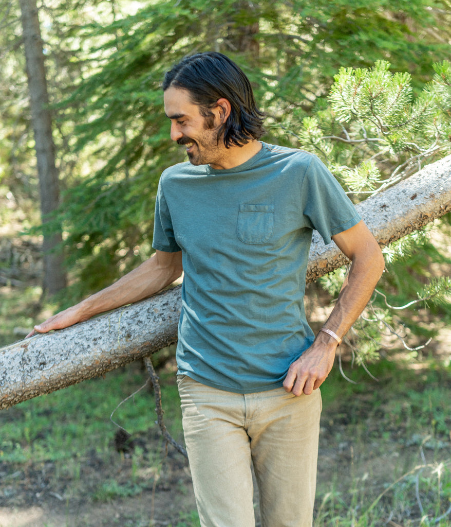 A man wearing a Men's Primary Pocket Tee in dark teal color by Deso Supply Co.