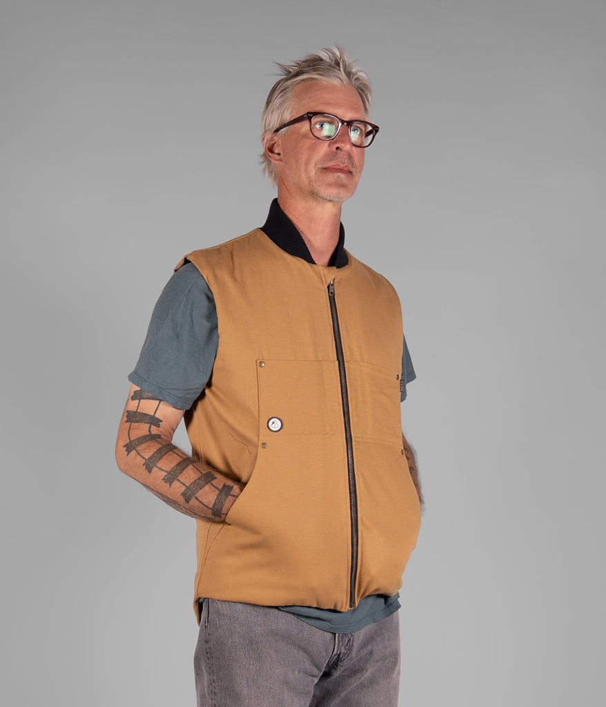 A man wearing a Hard Chore Vest in burley wood color by Deso Supply Co. 1