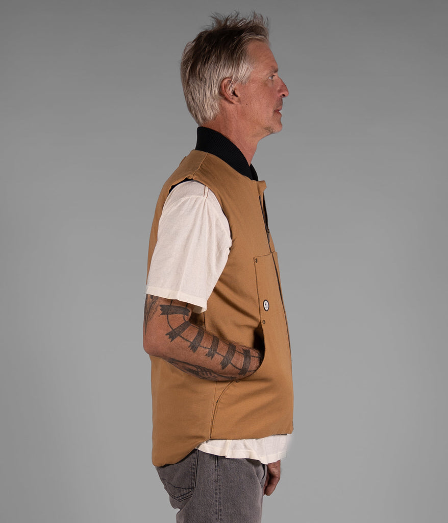 A man wearing a Hard Chore Vest in burley wood color by Deso Supply Co. in side view.