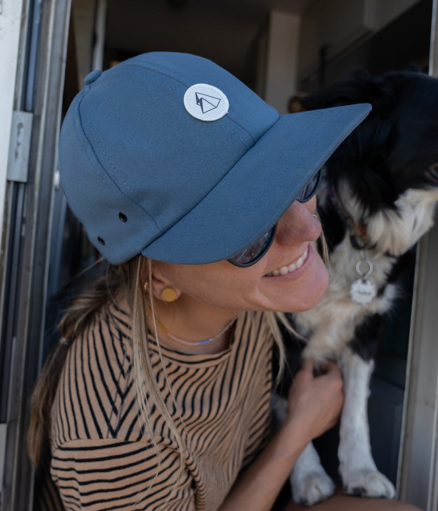 A woman with a dog wearing Hatchet 6 Panel Cap in orion blue by Deso Supply Co.