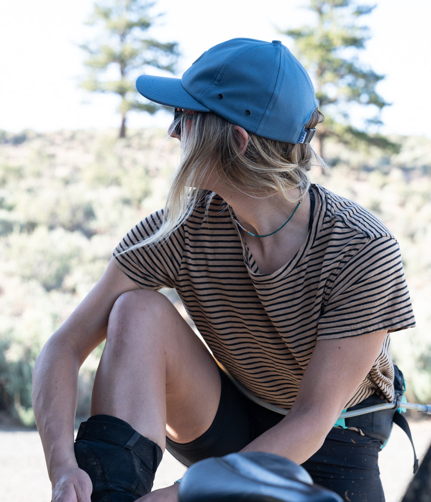 A woman wearing Hatchet 6 Panel Cap in orion blue in side view by Deso Supply Co.